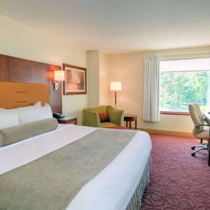 Double bed guest room in Sonesta Milwaukee West Wauwatosa, featuring armchair, window, and television.