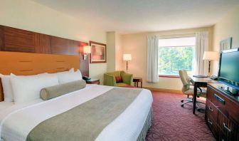 Double bed guest room in Sonesta Milwaukee West Wauwatosa, featuring armchair, window, and television.