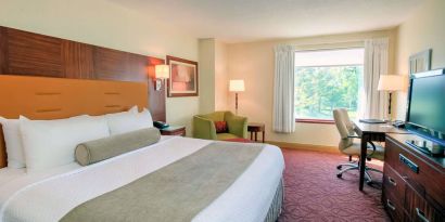 Double bed guest room in Sonesta Milwaukee West Wauwatosa, featuring armchair, window, and television.