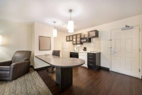 Guest room kitchen in Sonesta Simply Suites Hampton, including fridge-freezer, microwave, and a kitchen table and chair.