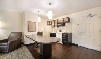 Guest room kitchen in Sonesta Simply Suites Hampton, including fridge-freezer, microwave, and a kitchen table and chair.