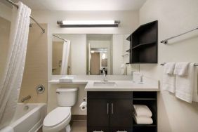 Guest bathroom in Sonesta Simply Suites Hampton, including bathtub, lavatory, mirror, and sink.