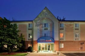 The hotel’s exterior features parking close to the front door and pleasant greenery, including bushes and trees.