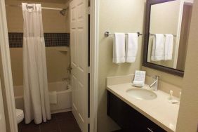 Guest bathroom in Sonesta ES Suites Dallas Las Colinas, featuring bath with a shower, lavatory, and mirror and sink.