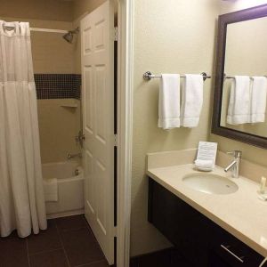 Guest bathroom in Sonesta ES Suites Dallas Las Colinas, featuring bath with a shower, lavatory, and mirror and sink.