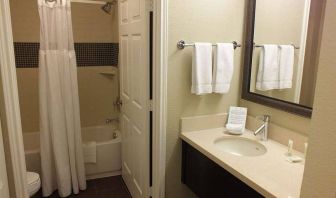 Guest bathroom in Sonesta ES Suites Dallas Las Colinas, featuring bath with a shower, lavatory, and mirror and sink.