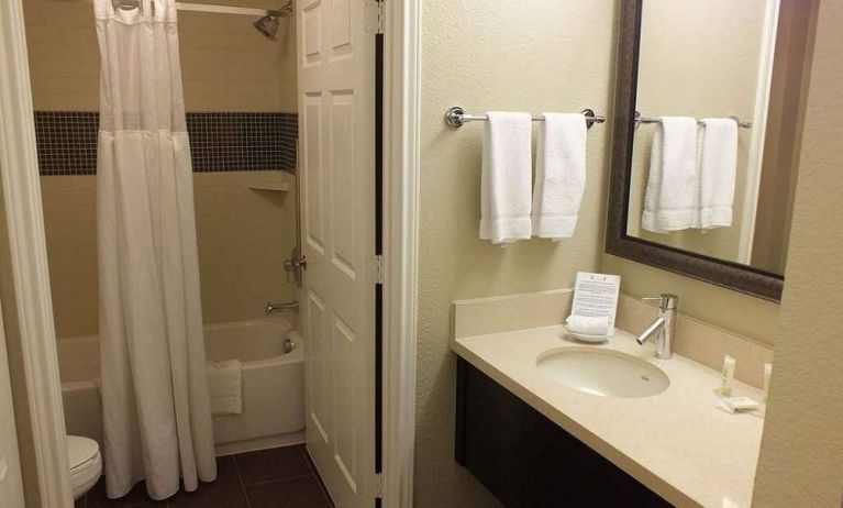 Guest bathroom in Sonesta ES Suites Dallas Las Colinas, featuring bath with a shower, lavatory, and mirror and sink.