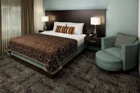 Double bed guest room in Sonesta ES Suites Dallas Las Colinas, featuring armchair, bedside lamps, and a window.