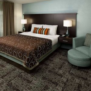 Double bed guest room in Sonesta ES Suites Dallas Las Colinas, featuring armchair, bedside lamps, and a window.