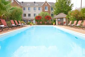 The outdoor pool of Sonesta ES Suites Dallas Las Colinas has tables and chairs, as well as sun loungers, by the side.