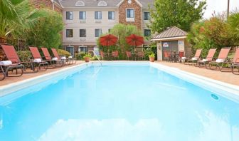 The outdoor pool of Sonesta ES Suites Dallas Las Colinas has tables and chairs, as well as sun loungers, by the side.