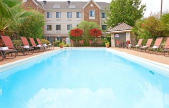 The outdoor pool of Sonesta ES Suites Dallas Las Colinas has tables and chairs, as well as sun loungers, by the side.