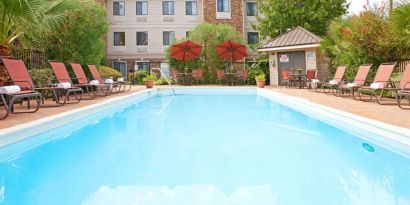 The outdoor pool of Sonesta ES Suites Dallas Las Colinas has tables and chairs, as well as sun loungers, by the side.