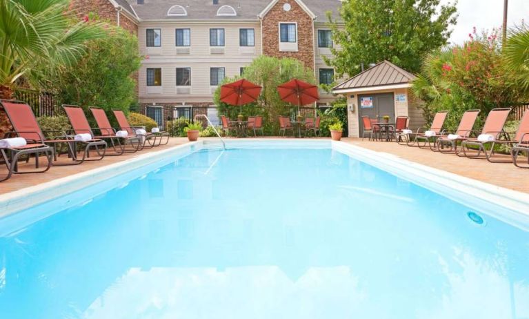 The outdoor pool of Sonesta ES Suites Dallas Las Colinas has tables and chairs, as well as sun loungers, by the side.