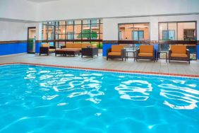 Sonesta Select Detroit Auburn Hills’ indoor pool has armchair and sofa seating by the side, plus large windows.