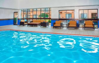 Sonesta Select Detroit Auburn Hills’ indoor pool has armchair and sofa seating by the side, plus large windows.