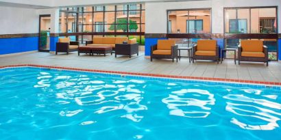 Sonesta Select Detroit Auburn Hills’ indoor pool has armchair and sofa seating by the side, plus large windows.