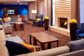 Sonesta Select Detroit Auburn Hills’ lobby lounge is furnished with sofas, armchairs, coffee tables, a fireplace and a wall-mounted TV.