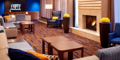 Sonesta Select Detroit Auburn Hills’ lobby lounge is furnished with sofas, armchairs, coffee tables, a fireplace and a wall-mounted TV.