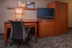 Sonesta Select Columbia guest room workspace, featuring desk, chair, and lamp, with a nearby TV.