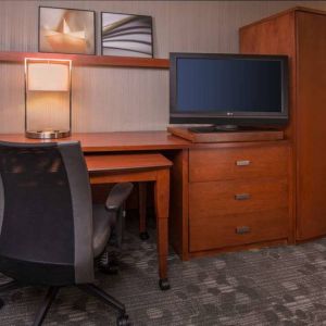 Sonesta Select Columbia guest room workspace, featuring desk, chair, and lamp, with a nearby TV.