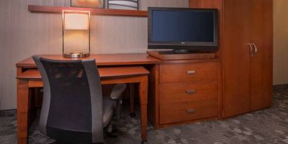 Sonesta Select Columbia guest room workspace, featuring desk, chair, and lamp, with a nearby TV.