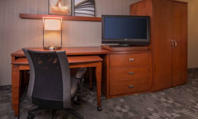 Sonesta Select Columbia guest room workspace, featuring desk, chair, and lamp, with a nearby TV.