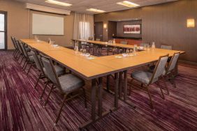 Meeting room in Sonesta Select Columbia, with tables arranged in a U-shape, seating for over a dozen attendees, and a whiteboard.