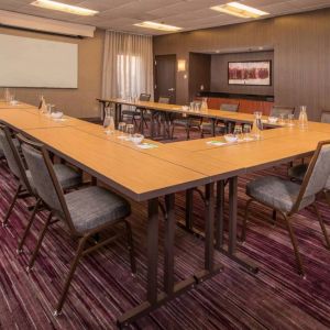 Meeting room in Sonesta Select Columbia, with tables arranged in a U-shape, seating for over a dozen attendees, and a whiteboard.