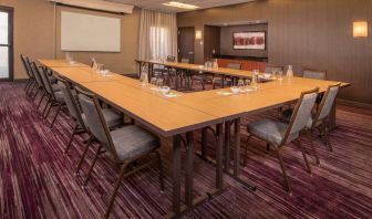 Meeting room in Sonesta Select Columbia, with tables arranged in a U-shape, seating for over a dozen attendees, and a whiteboard.