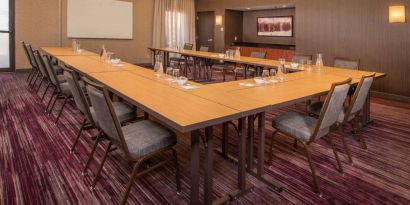 Meeting room in Sonesta Select Columbia, with tables arranged in a U-shape, seating for over a dozen attendees, and a whiteboard.