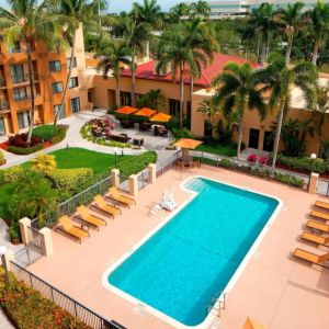 Sonesta Select Boca Raton’s outdoor pool is equipped with a lift, and has sun loungers by the side plus pleasant greenery beyond the fence.