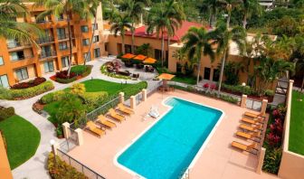 Sonesta Select Boca Raton’s outdoor pool is equipped with a lift, and has sun loungers by the side plus pleasant greenery beyond the fence.