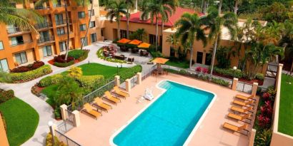 Sonesta Select Boca Raton’s outdoor pool is equipped with a lift, and has sun loungers by the side plus pleasant greenery beyond the fence.