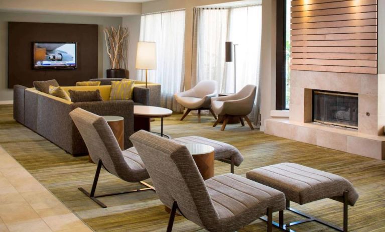 Sonesta Select Boca Raton’s lobby lounge has sofas, chairs, and reclined seats, plus coffee tables, a fireplace, and a wall-mounted television.