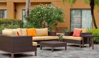 The hotel’s patio is furnished with armchair and sofa seating, plus coffee tables, and is surrounded by greenery.