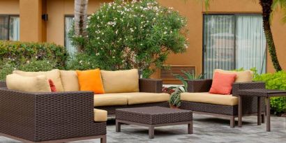 The hotel’s patio is furnished with armchair and sofa seating, plus coffee tables, and is surrounded by greenery.