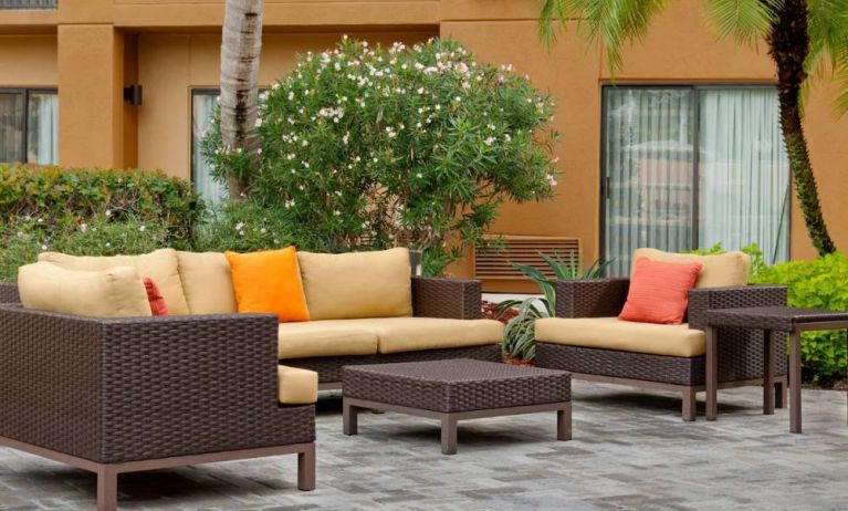 The hotel’s patio is furnished with armchair and sofa seating, plus coffee tables, and is surrounded by greenery.