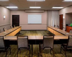 Hotel meeting room, featuring tables arranged in a U-shape, seating for a dozen attendees, and a whiteboard.