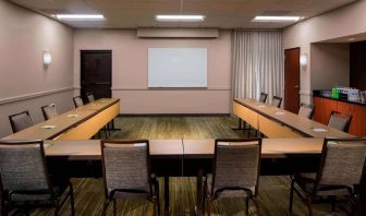 Hotel meeting room, featuring tables arranged in a U-shape, seating for a dozen attendees, and a whiteboard.