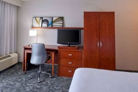 Sonesta Select Indianapolis Carmel guest room workspace, furnished with bed and TV, plus desk, chair, and lamp.