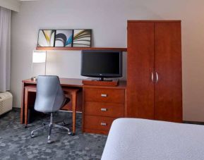 Sonesta Select Indianapolis Carmel guest room workspace, furnished with bed and TV, plus desk, chair, and lamp.