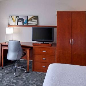 Sonesta Select Indianapolis Carmel guest room workspace, furnished with bed and TV, plus desk, chair, and lamp.