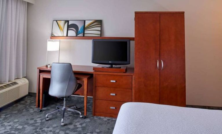 Sonesta Select Indianapolis Carmel guest room workspace, furnished with bed and TV, plus desk, chair, and lamp.