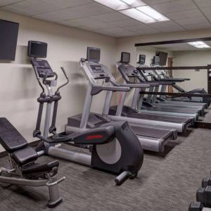 The hotel fitness center is equipped with free weights, a range of exercise machines, and a wall-mounted TV.