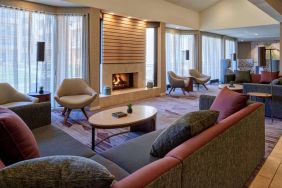 The lobby lounge in Sonesta Select Indianapolis Carmel has a mix of comfy chairs and large sofas, plus coffee tables and a fireplace.