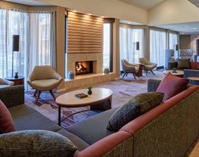 The lobby lounge in Sonesta Select Indianapolis Carmel has a mix of comfy chairs and large sofas, plus coffee tables and a fireplace.