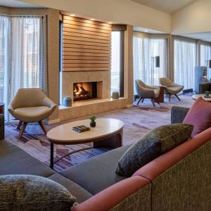 The lobby lounge in Sonesta Select Indianapolis Carmel has a mix of comfy chairs and large sofas, plus coffee tables and a fireplace.