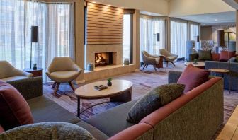 The lobby lounge in Sonesta Select Indianapolis Carmel has a mix of comfy chairs and large sofas, plus coffee tables and a fireplace.