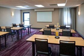 Hotel meeting room with tables, in a classroom format, facing a whiteboard and window.